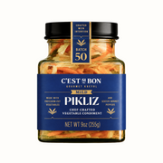 Jar of C'est Si Bon Pikliz vegetable condiment with a blue label on a white background
