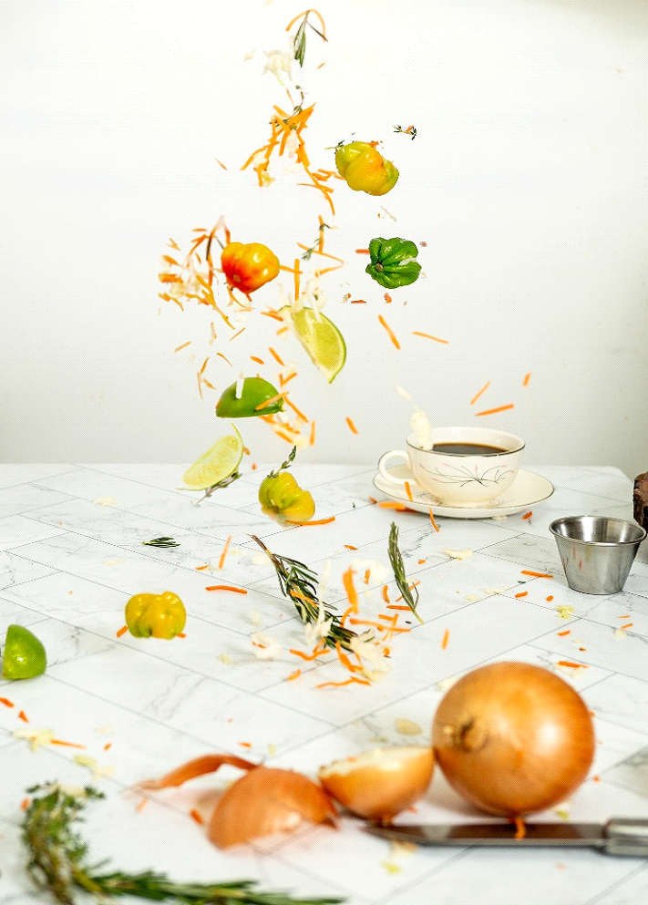 Falling vegetables and a cup of coffee on a white tablecloth.