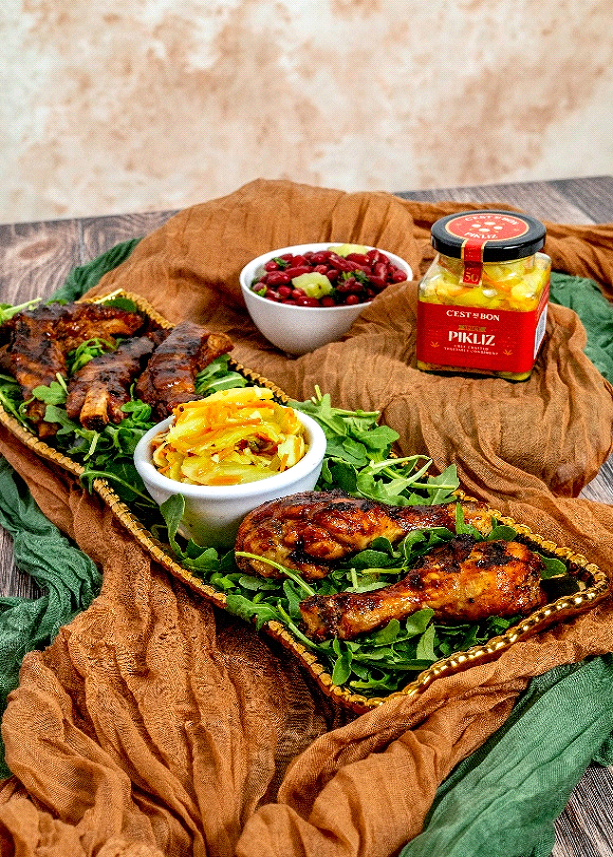 Plated dish with grilled chicken, salad, and side dishes on a rustic wooden table.