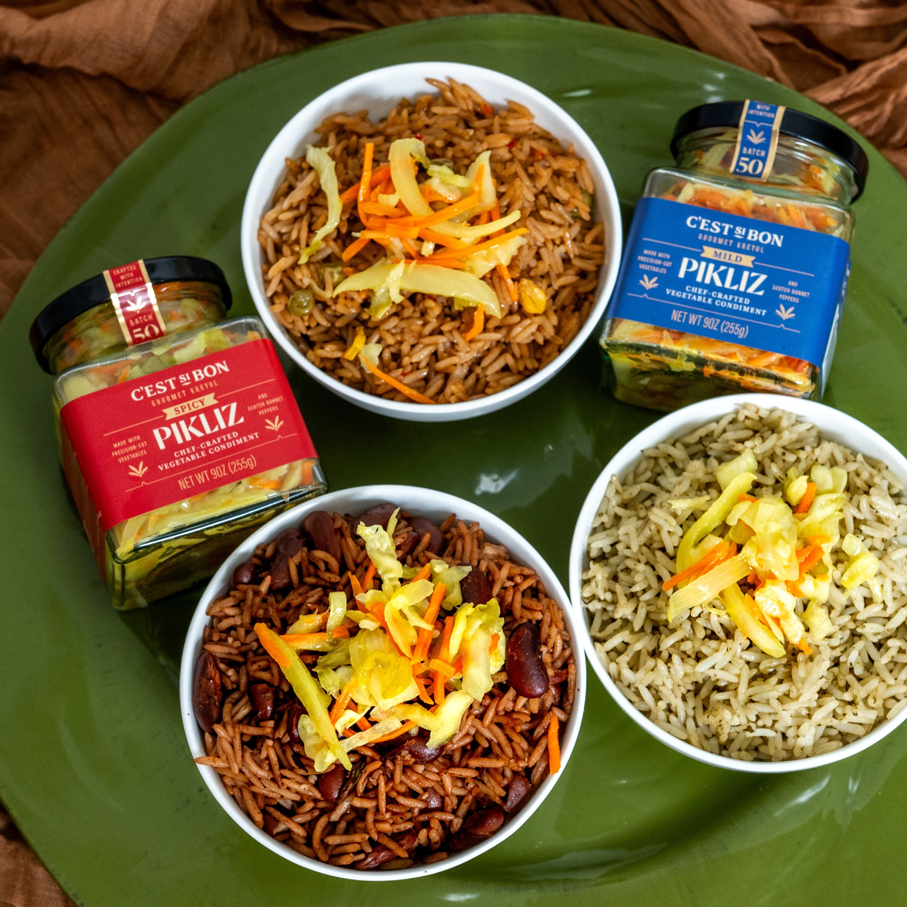 Three bowls of rice and beans with pickles on a green tray.